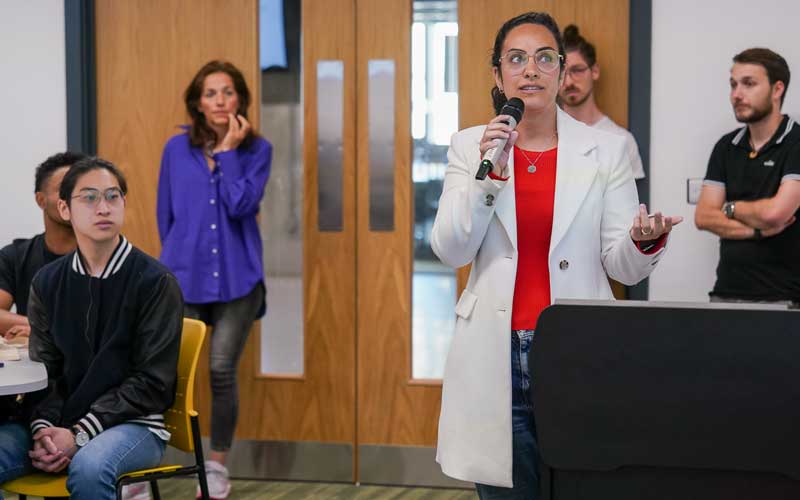 Female partner stood holding a microphone in a room of people